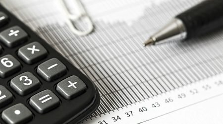 Close-up of a calculator and pen on a bar graph, representing finance and accounting.